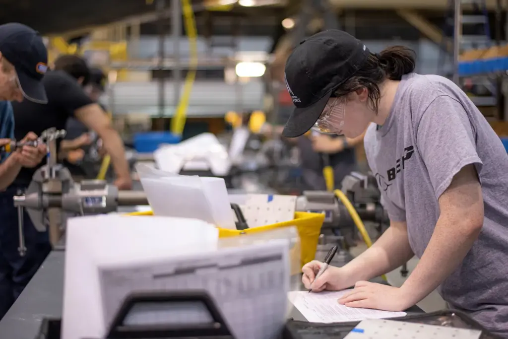 High School students working on a project on the factory floor.